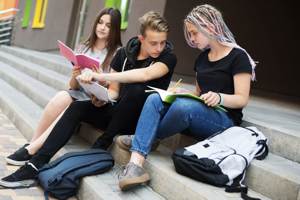 3 studenten op stoep voor school